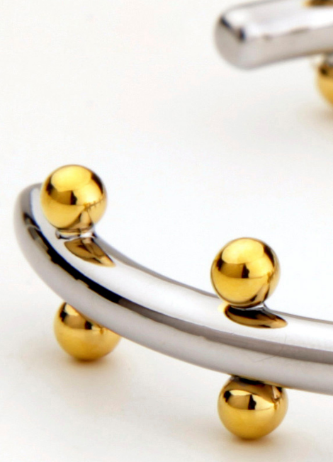 The Gloria Golden Drops Two Tone Bangle is crafted for the modern woman who loves timeless elegance with a twist. Its sleek two-tone finish highlights the brilliance of 18K gold plating, creating a striking contrast that pairs beautifully with any outfit. Whether stacked with other bangles or worn solo, this piece exudes effortless sophistication.